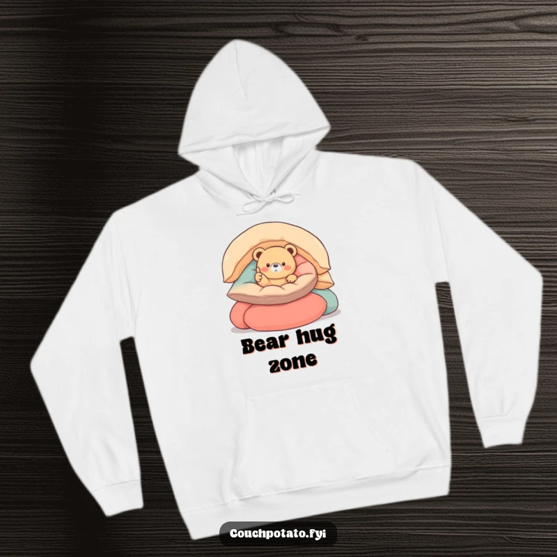 Funny round bear hoodie depicting a small, round bear nestled in cushions, giving a thumbs up, designed for ultimate coziness and joy.