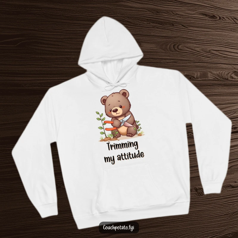 Funny bear cub hoodie, a determined bear cub meticulously uses shears to prune a small bush with great care.